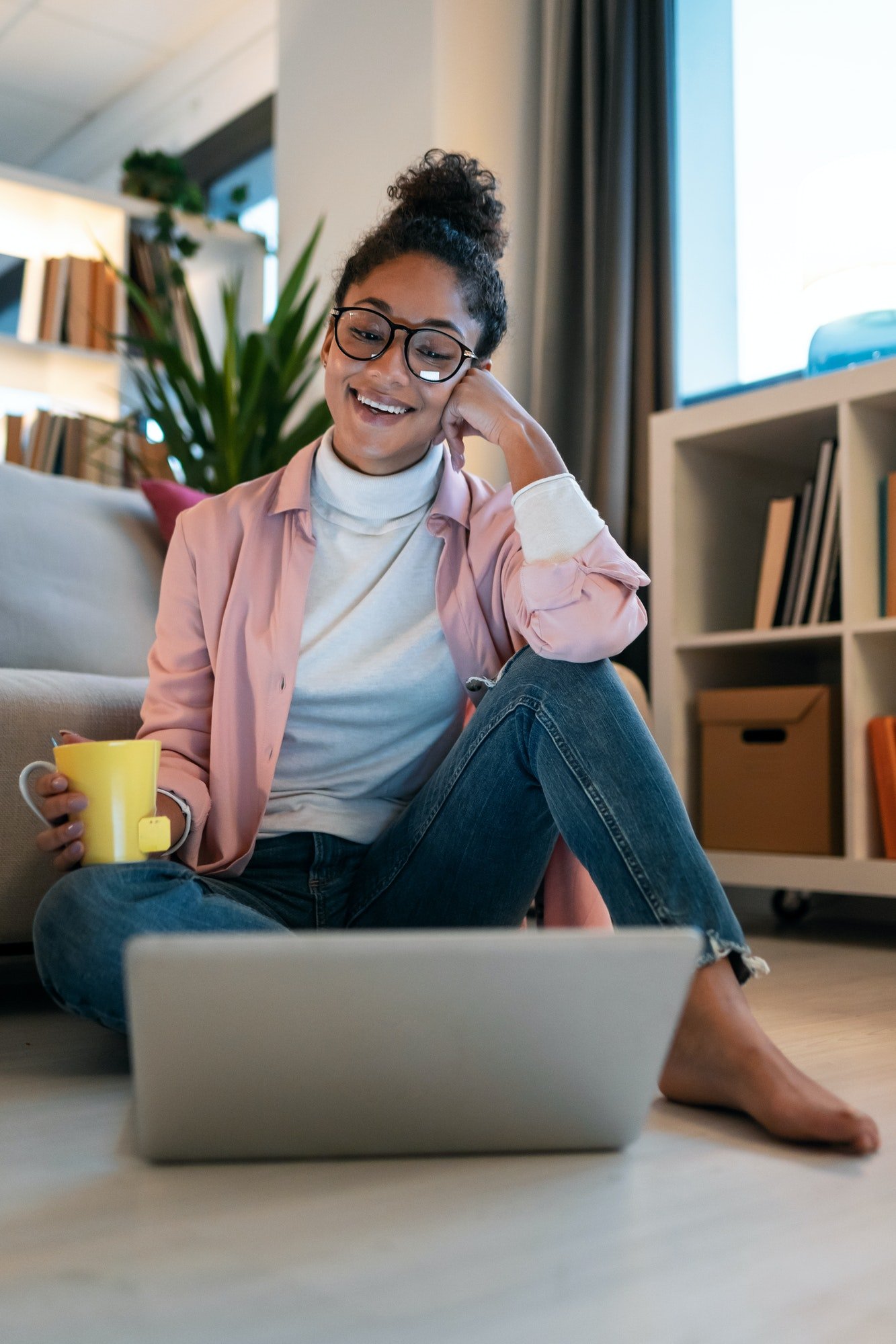 Entrepreneur woman working with laptop while drinking coffee sitting on the floor in the office.
